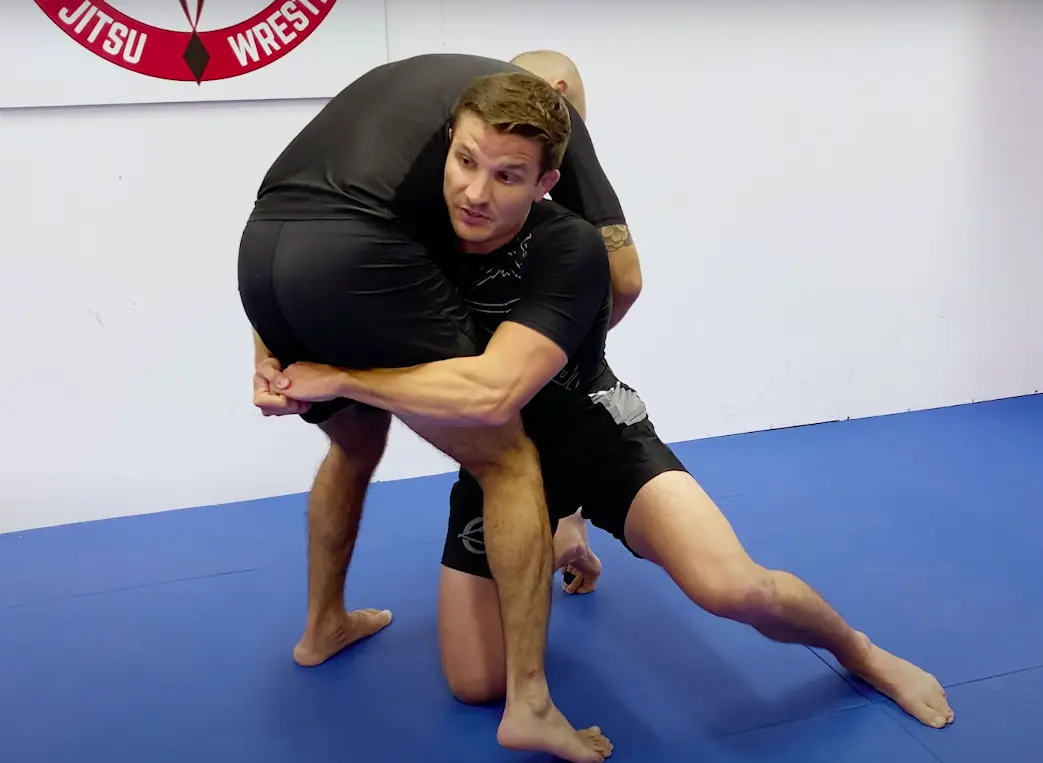 One player is on one knee and has their hands clasped behind the thighs of the standing player.